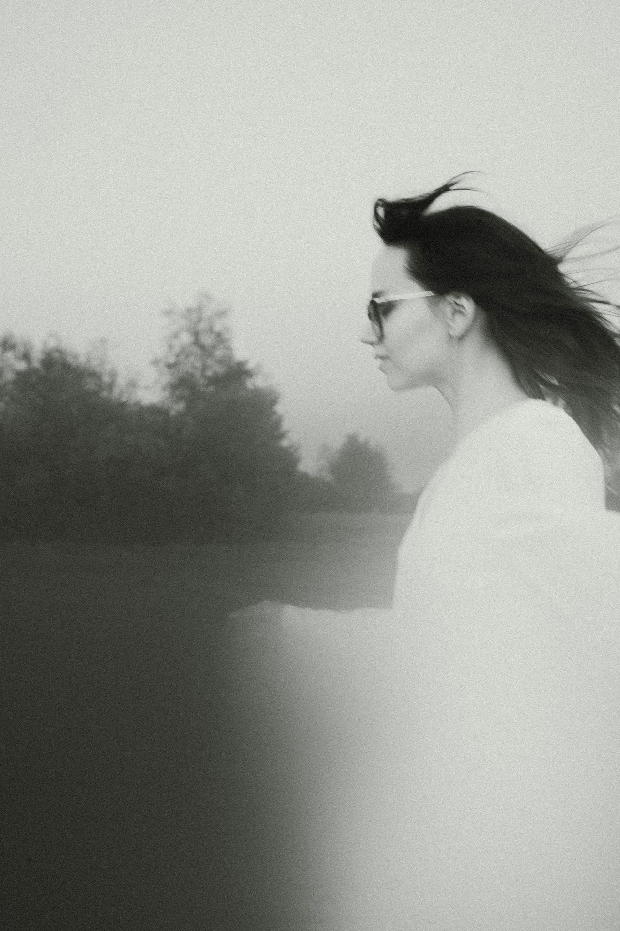 A black and white photo of a woman with her hair blowing in the wind